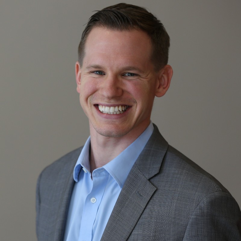 A man in a suit and tie smiling for the camera.